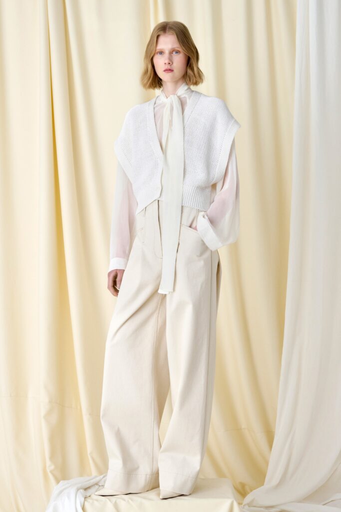 A relaxed white cotton long-sleeve top paired with wide-leg beige pants.