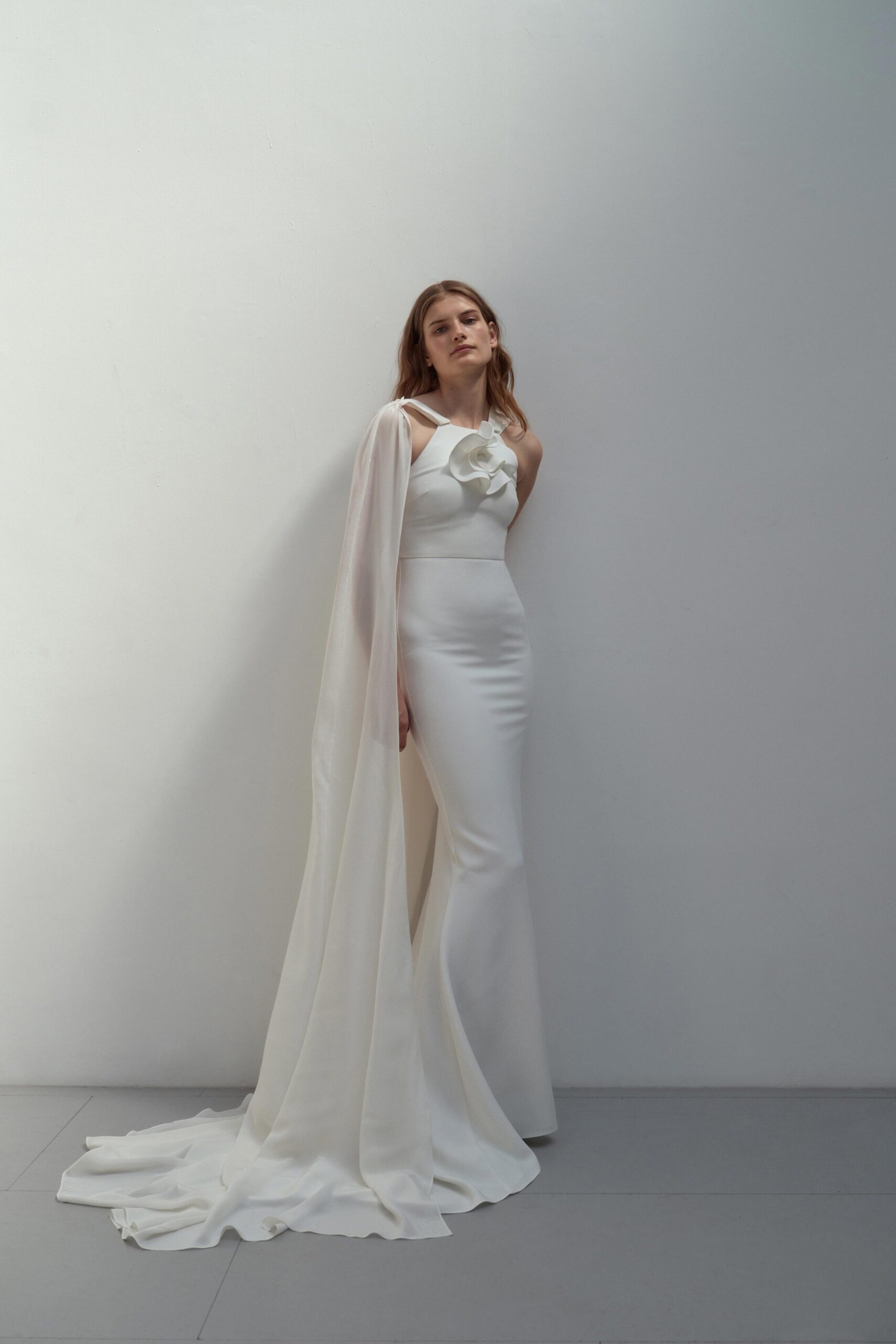 A fitted white silk gown with a high neckline and flared silhouette.