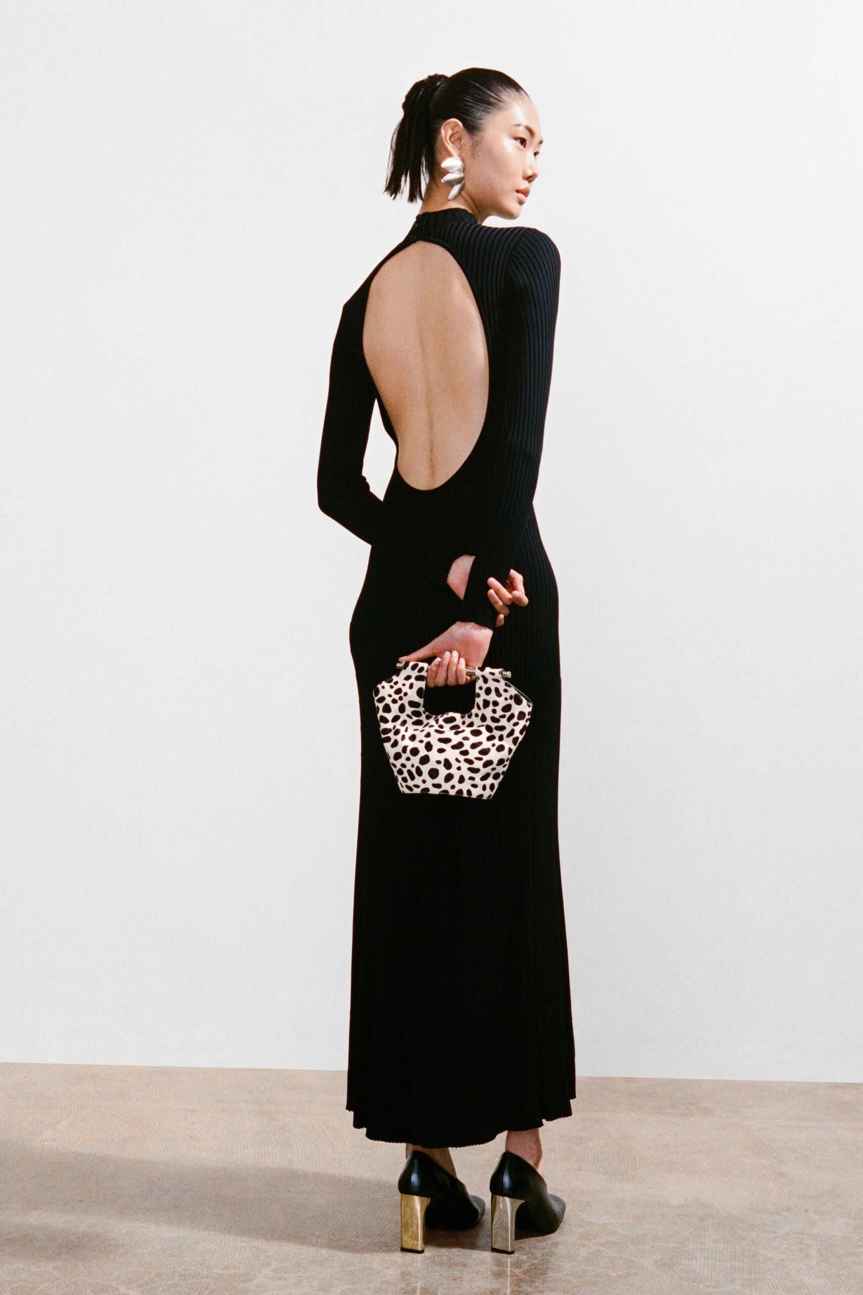 A fitted black dress with long sleeves and a backless design, featuring a maxi silhouette.