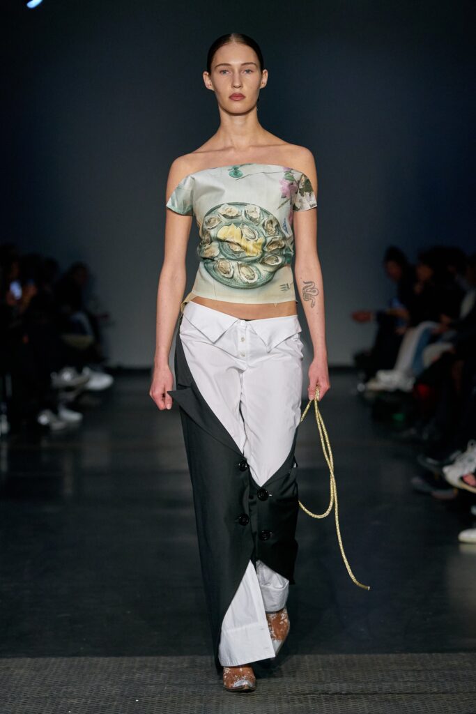 A relaxed fit asymmetric black and white sleeveless top paired with relaxed pants.