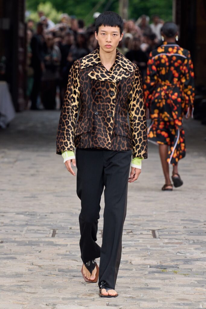 A fitted brown animal-print jacket with long sleeves paired with black fitted pants.
