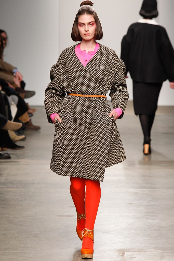 A relaxed black checked coat dress with long sleeves and a collared neckline.