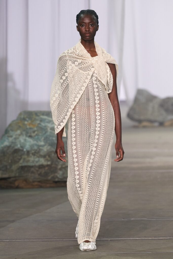 A relaxed white lace dress with a high neckline and sheer detailing.
