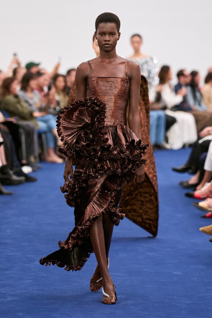 A fitted brown silk dress with a sleeveless design and asymmetric ruffled details.