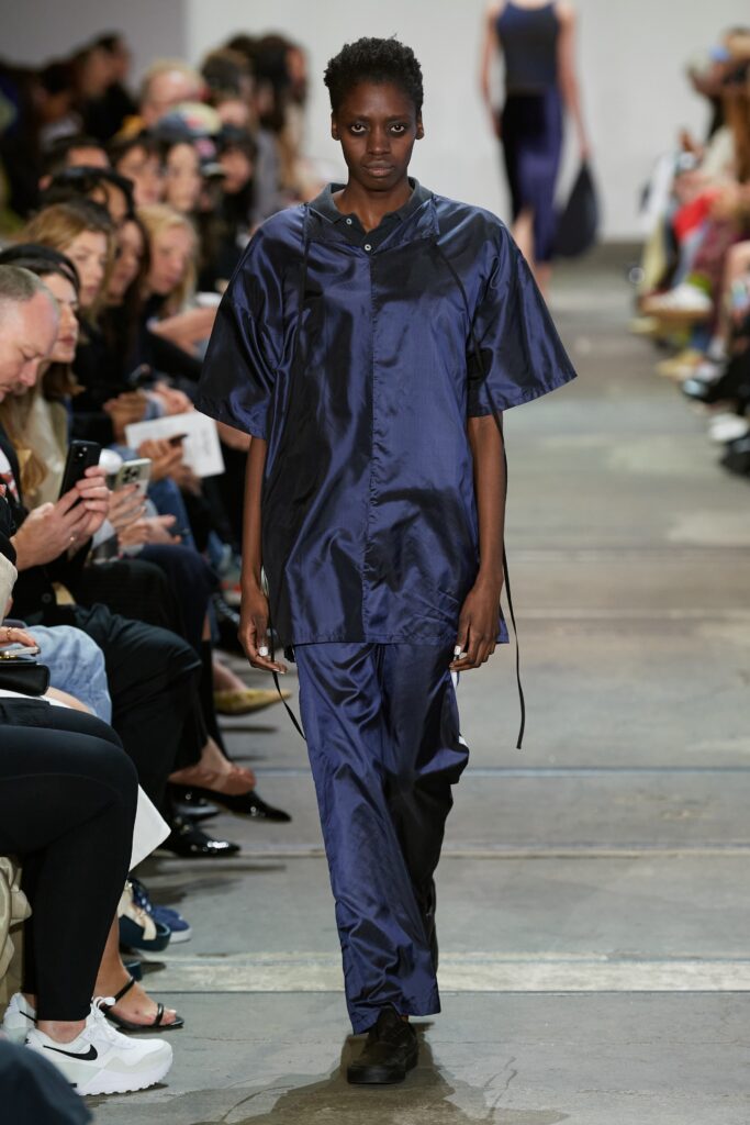 A relaxed blue silk jacket with short sleeves paired with wide-leg pants.
