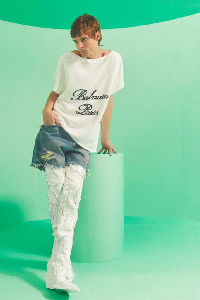 An oversized white cotton top paired with distressed blue denim shorts for a casual look.