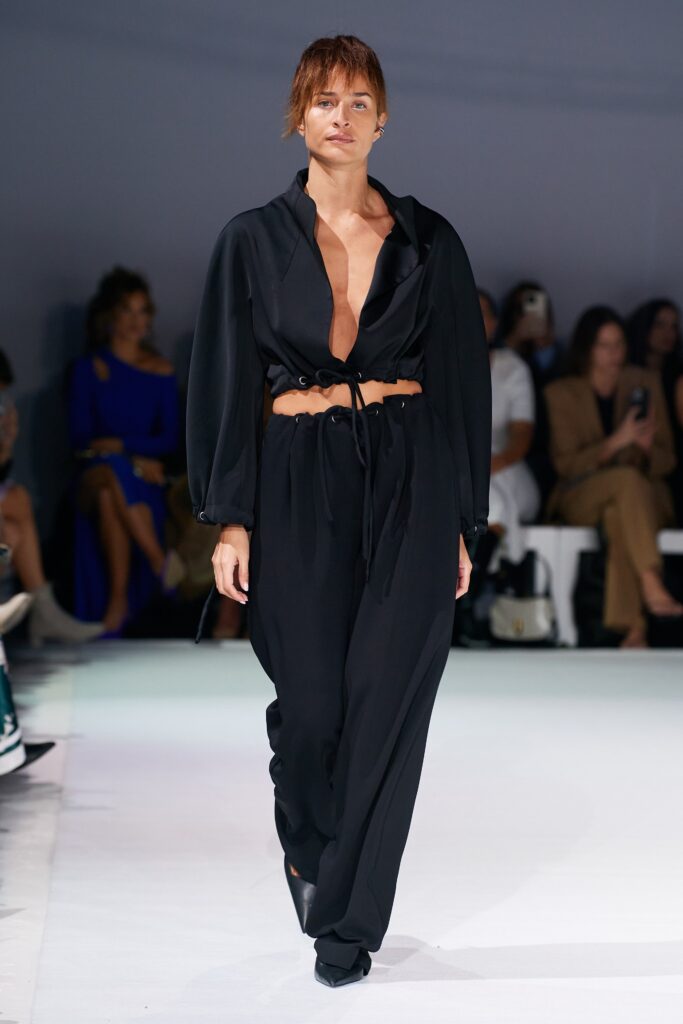 A relaxed black silk jumpsuit with long sleeves and a V-neckline, featuring a belted waist.