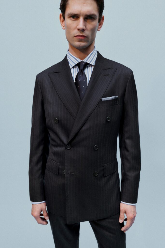 A tailored black wool suit with long sleeves and a double-breasted design featuring stripes.