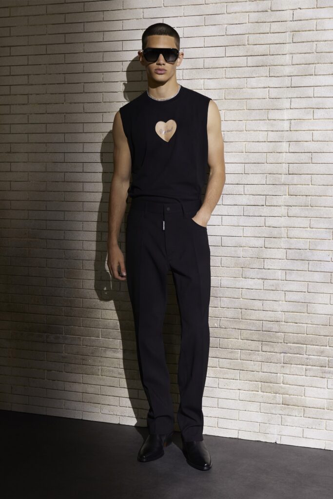 A fitted black sleeveless top with a printed detail paired with high-waisted black pants.