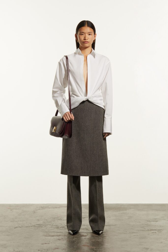A fitted white long-sleeve shirt with a collared design paired with a gray asymmetric skirt.