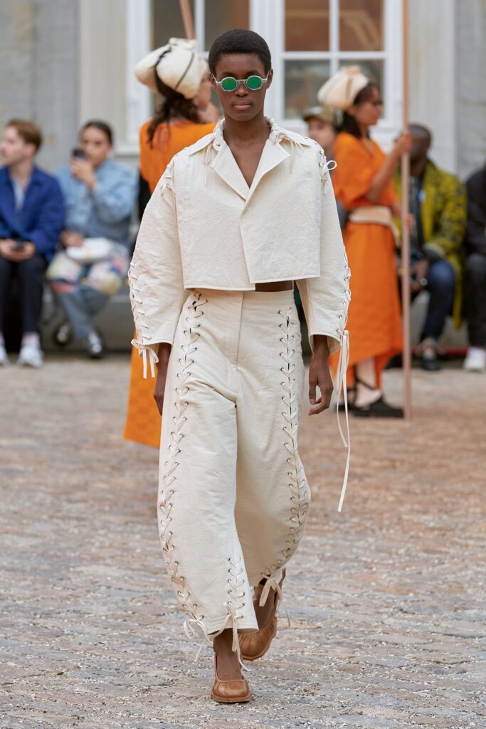 A relaxed white cotton top with long sleeves and lace-up pants, creating a unique silhouette.