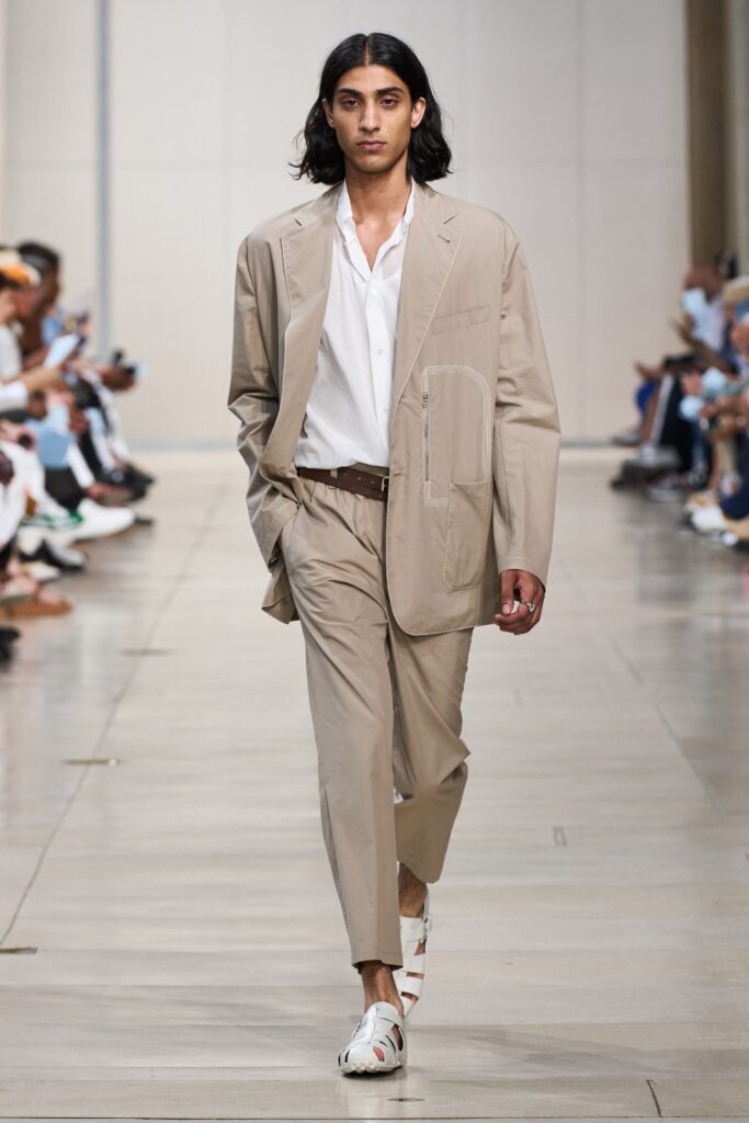A relaxed beige cotton jacket with long sleeves and collared neckline paired with straight-leg pants.
