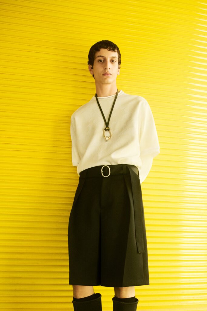 A relaxed white short-sleeve top paired with high-waisted black shorts featuring an asymmetric design.