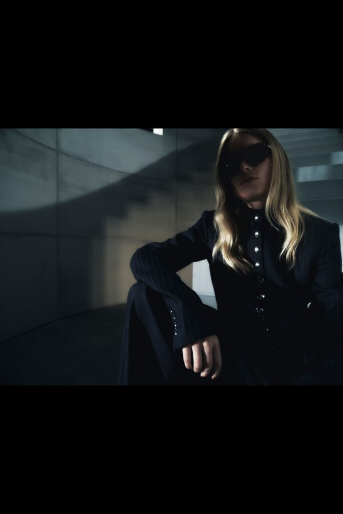 A fitted black cotton suit with long sleeves and a collared design, featuring button details.