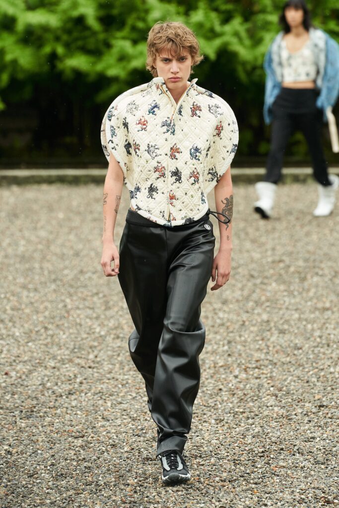 A fitted black leather pants paired with a printed long-sleeve jacket featuring a collared design.