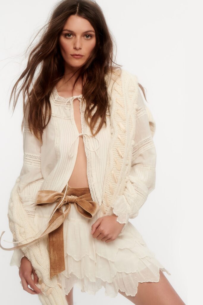 A fitted white sleeveless dress with a V-neckline and tiered design details.
