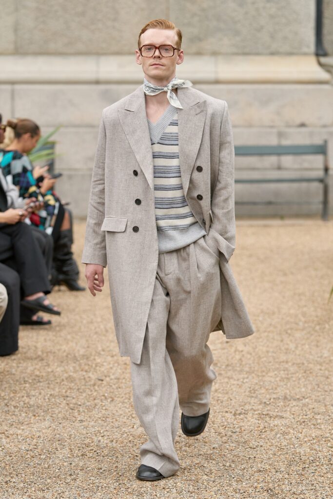 A relaxed beige linen suit paired with a striped long-sleeve shirt and v-neckline.