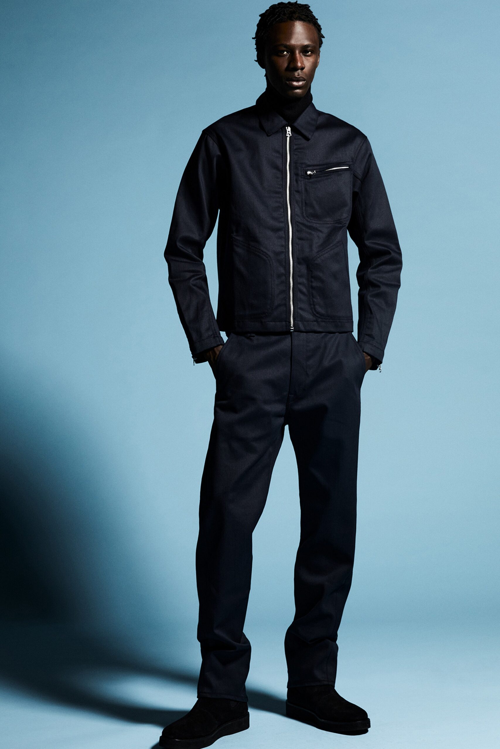 A fitted black denim jacket with a zippered detail paired with matching fitted pants.