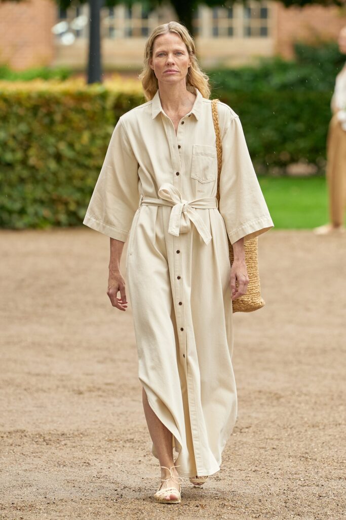 A relaxed beige cotton dress with long sleeves, a collared neckline, and a belted waist.