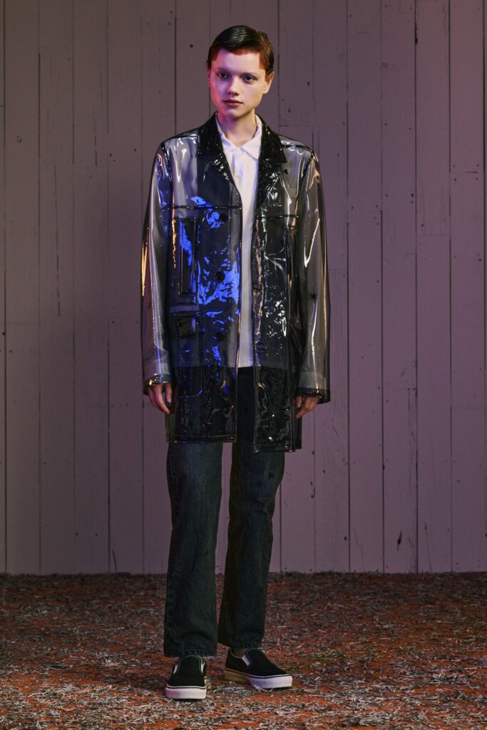 A relaxed-fit transparent black jacket paired with straight-leg denim pants.