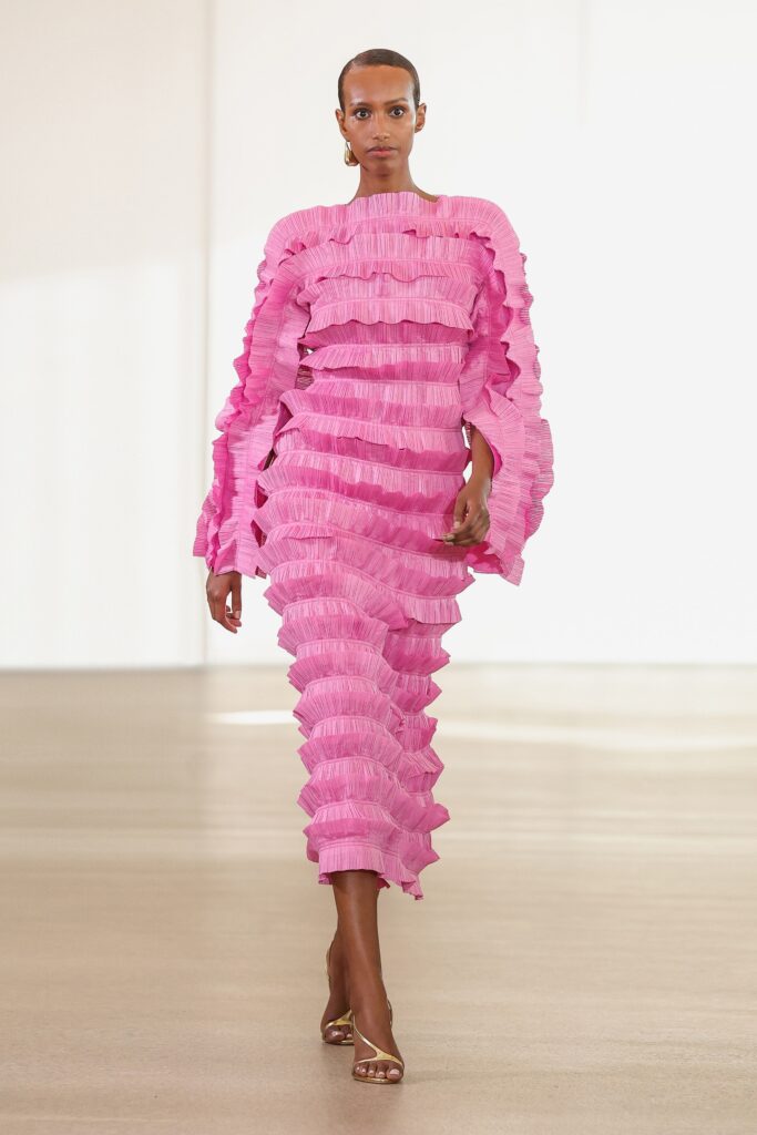 A fitted pink dress with long sleeves and pleated design details for a striking look.