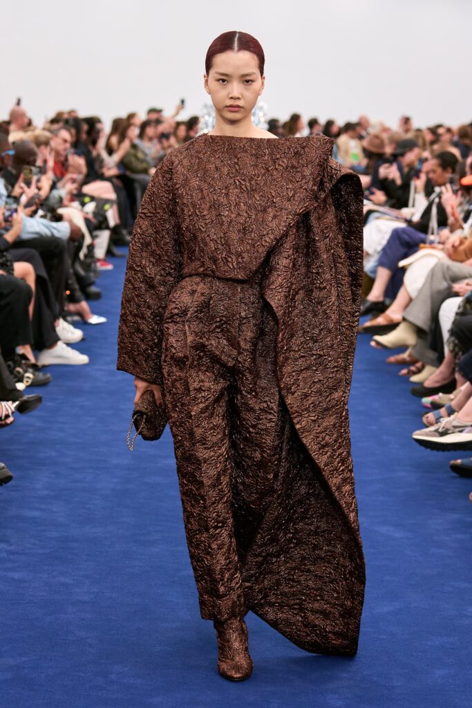 A relaxed brown silk jumpsuit with long sleeves and an asymmetric design.