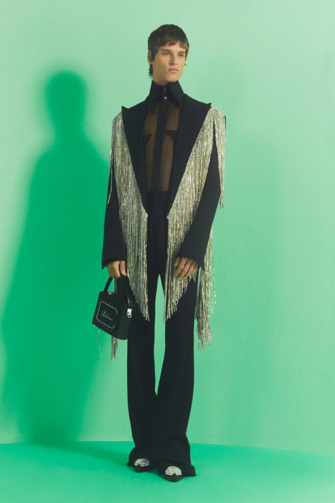 A fitted black silk jacket with fringed details paired with matching pants.