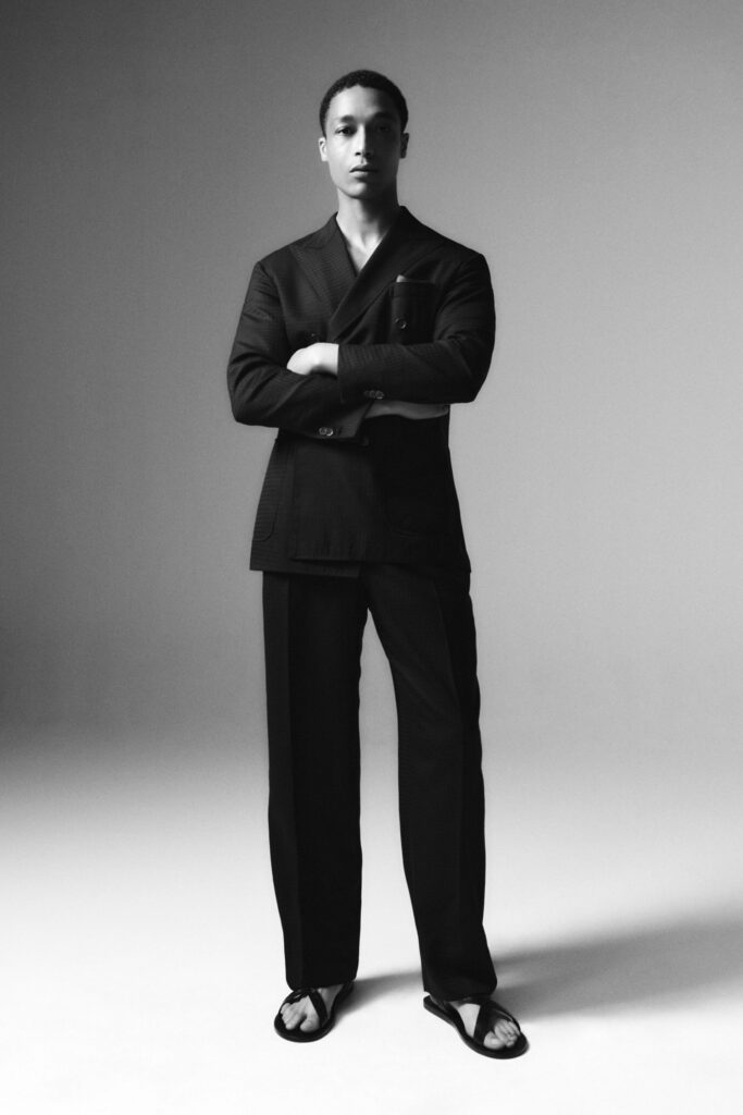 A tailored black suit with long sleeves and a collared design, featuring buttoned details.