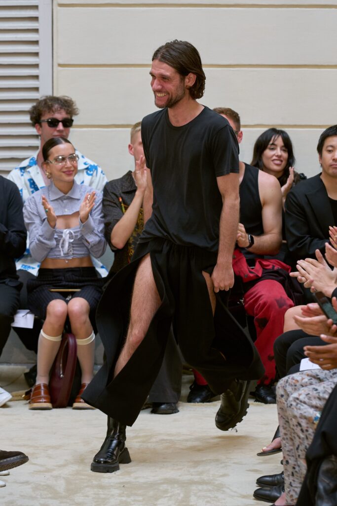 A relaxed black cotton sleeveless dress with a V-neckline and asymmetric design.