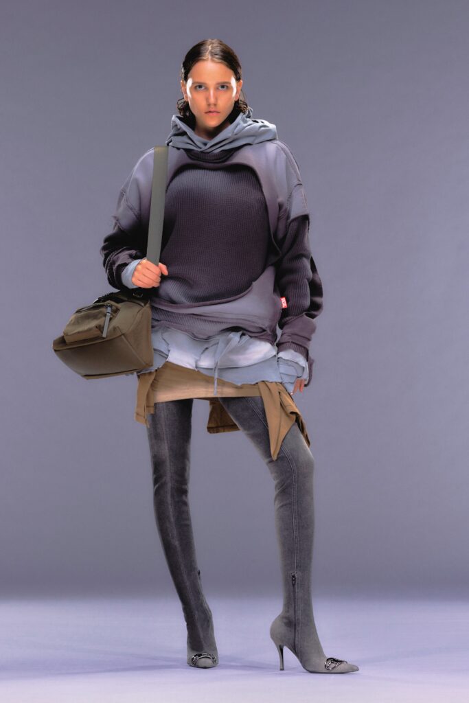 A relaxed gray hoodie with long sleeves and a hood, layered over a skirt.