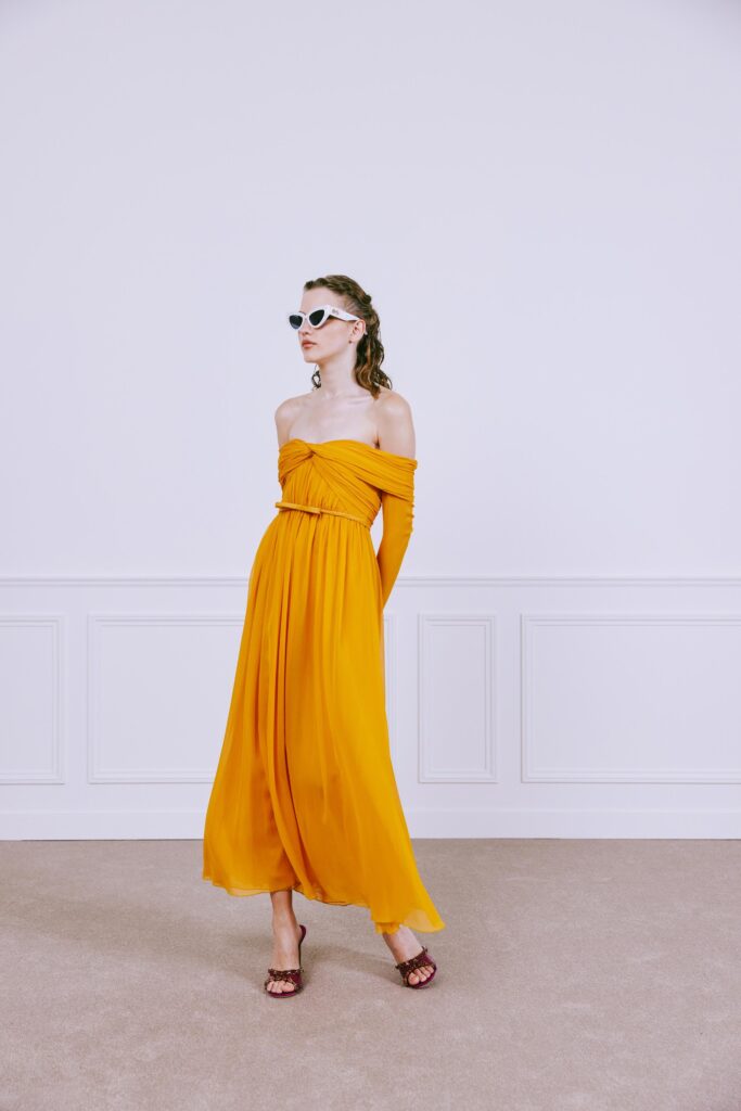 A fitted yellow chiffon off-shoulder dress with a flowing maxi silhouette.