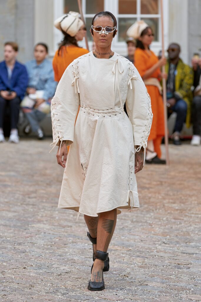 A relaxed beige cotton dress with long sleeves and a tiered design.