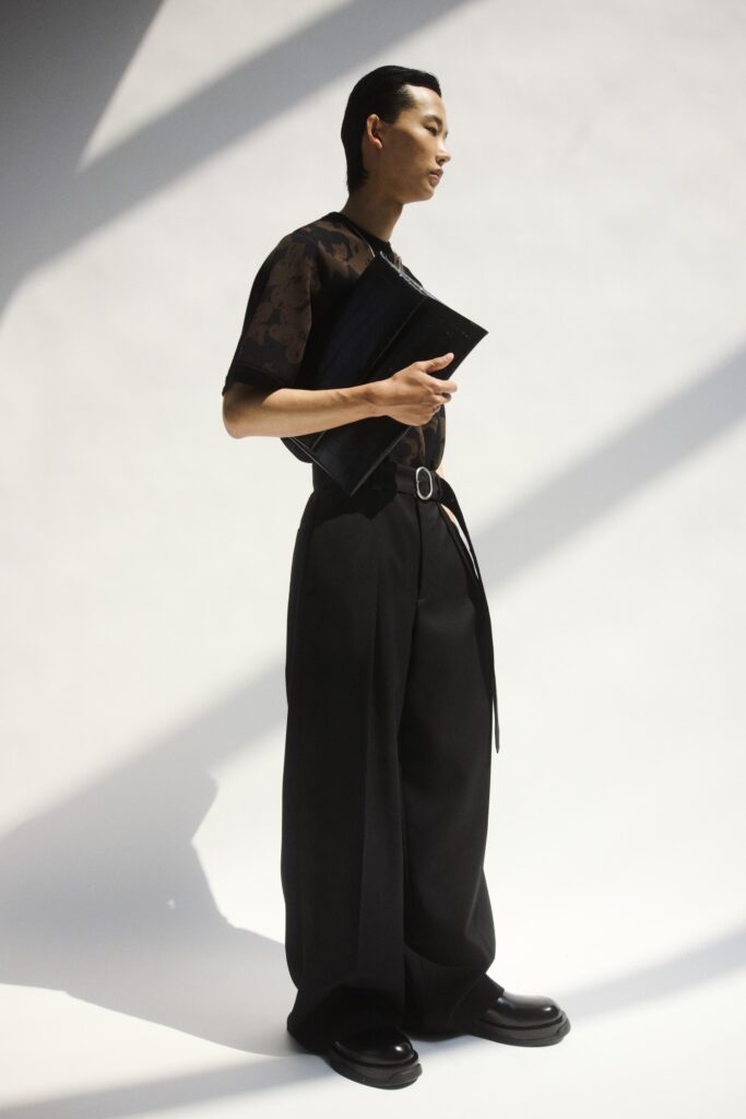 A relaxed black top with short sleeves and asymmetric design paired with black pants.