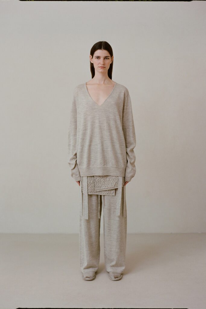 A relaxed gray cotton sweater with a V-neck and layered design paired with matching pants.