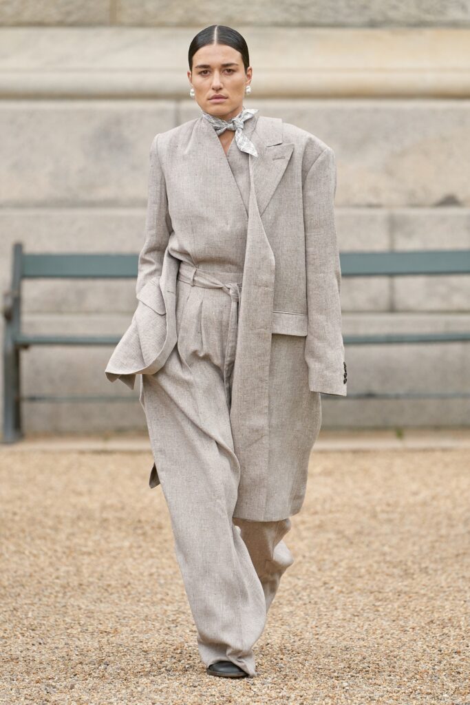 A relaxed beige linen suit featuring a long-sleeve collared jacket and buttoned details.