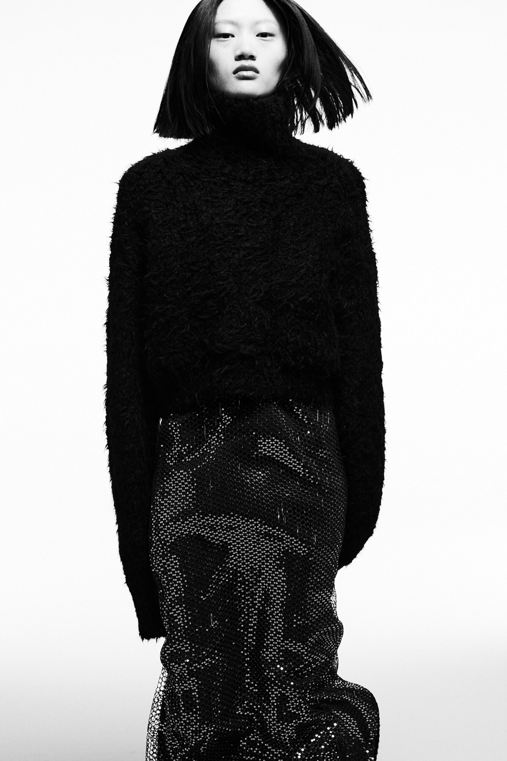 An oversized black wool sweater paired with a fitted sequin pencil skirt.