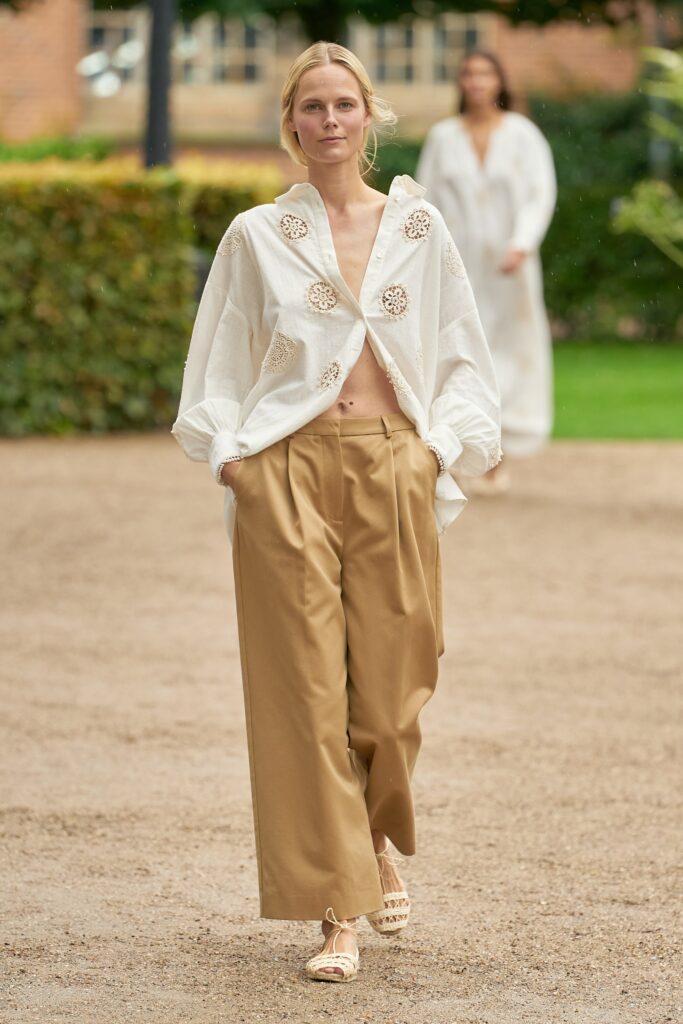 A relaxed white long-sleeve collared shirt with embroidery paired with wide-leg beige pants.