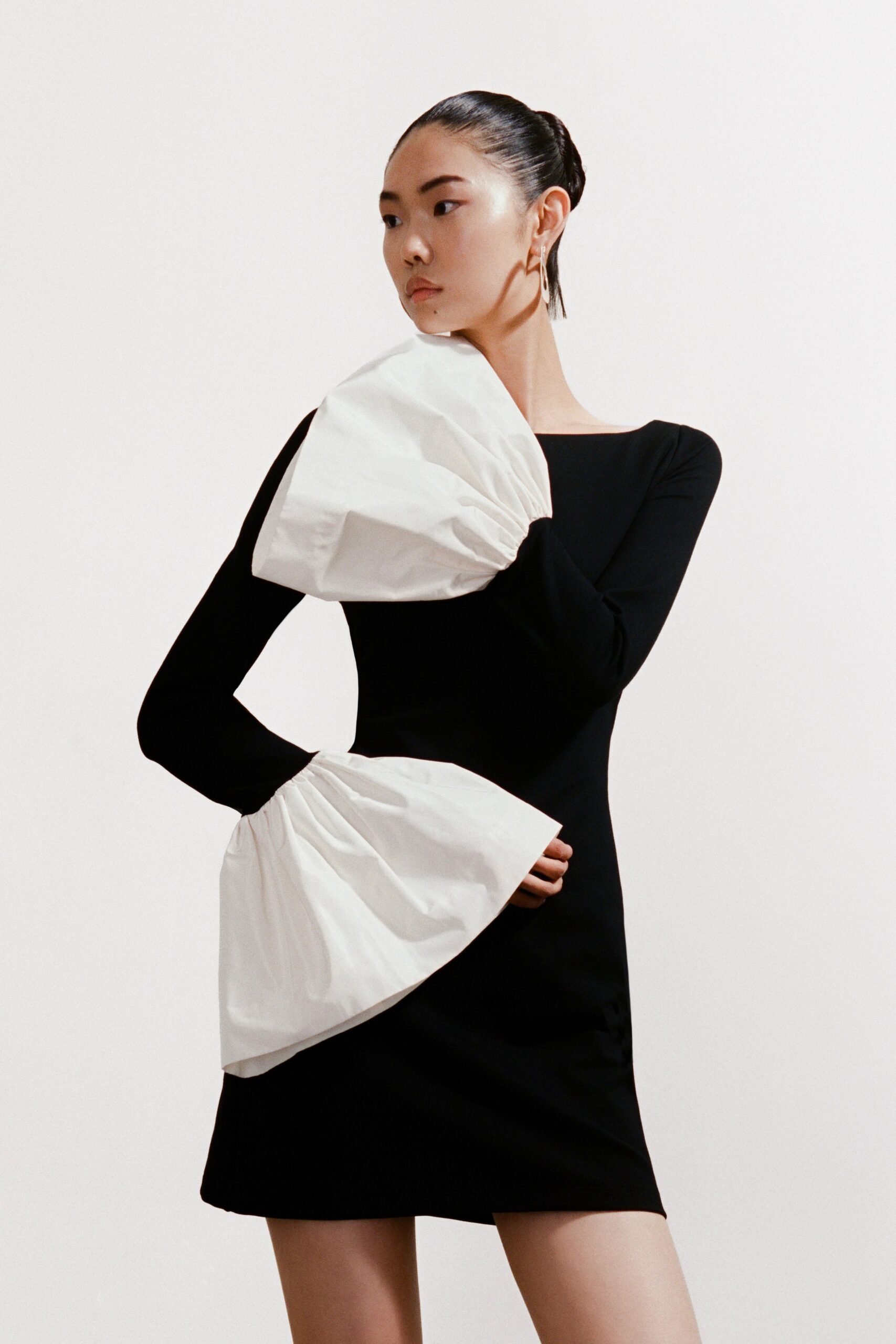 A fitted black dress featuring long bell sleeves and an asymmetric design.