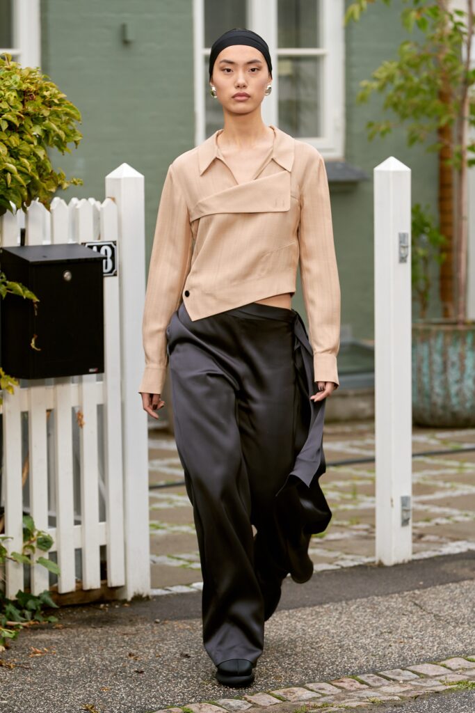 A relaxed beige collared top paired with wide-leg black pants featuring an asymmetric design.