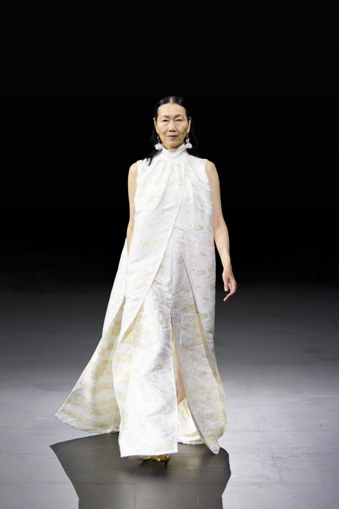 An asymmetric white silk sleeveless dress featuring elegant draping and a flowing silhouette.
