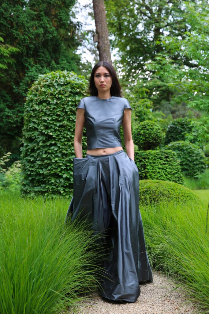 A fitted gray leather top with short sleeves paired with an asymmetric skirt.