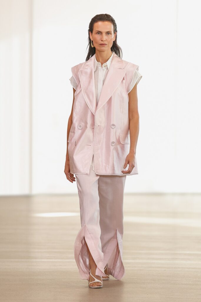 A relaxed pink silk sleeveless vest paired with pants featuring slits.