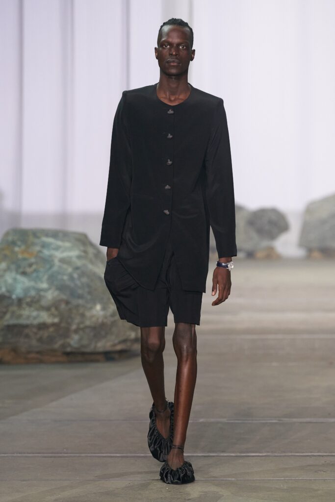 A relaxed black dress with long sleeves and an asymmetric design.