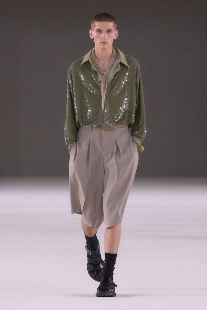 A relaxed green sequined long-sleeve shirt paired with pleated beige shorts.