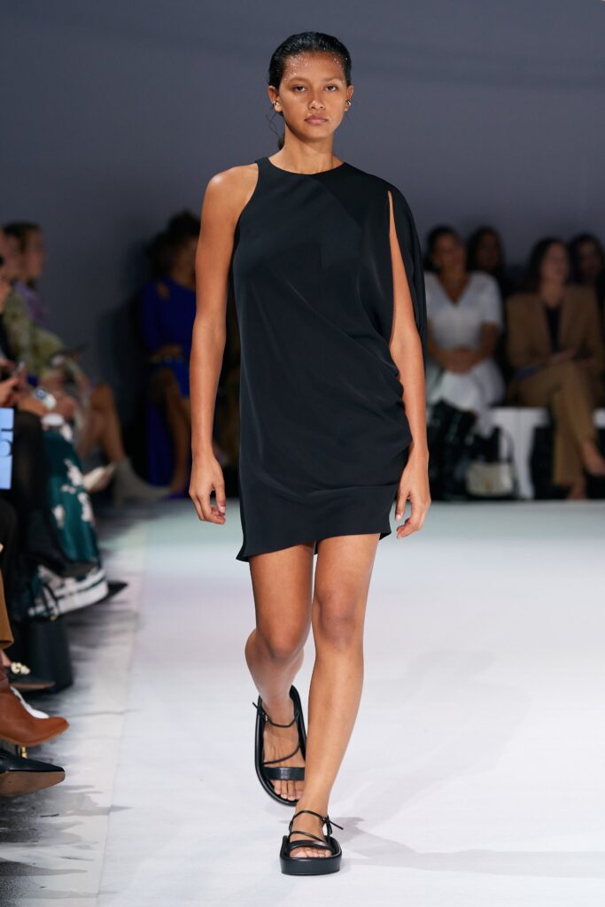 A fitted black silk dress with an asymmetric design and sleeveless construction.
