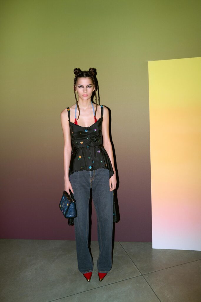 A relaxed black sleeveless top layered over gray denim pants with an asymmetric design.