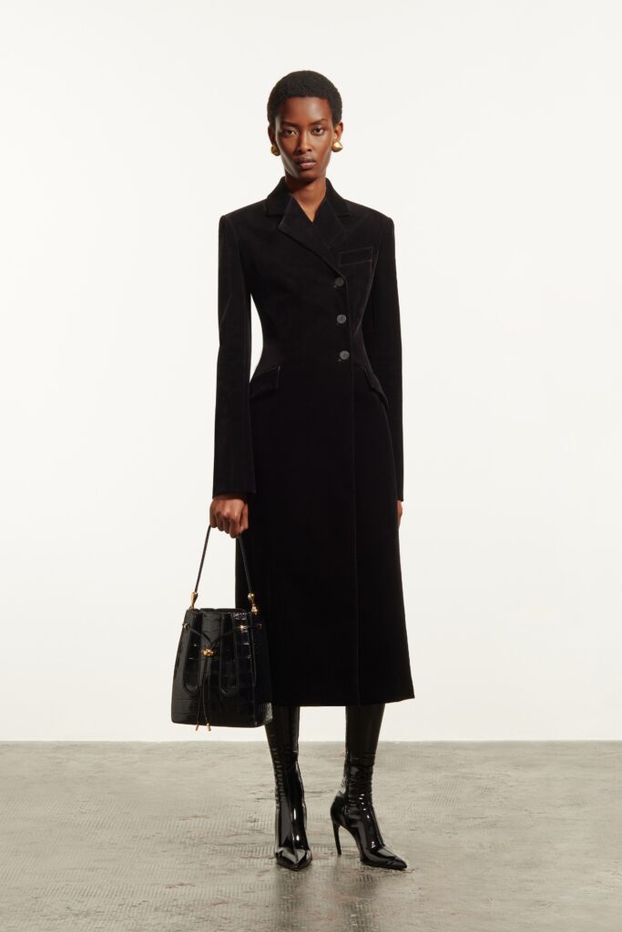 A fitted black velvet coat with long sleeves and a collared design featuring button details.