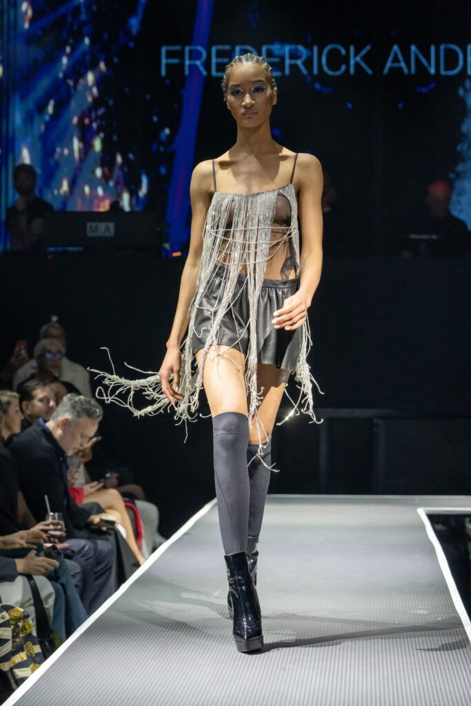 A fitted black leather sleeveless dress with a V-neckline and fringed detailing.