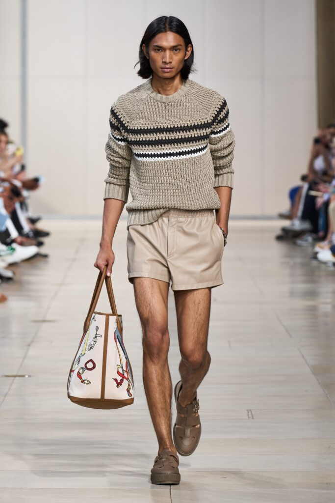 A relaxed beige striped sweater paired with pleated brown shorts for a casual look.