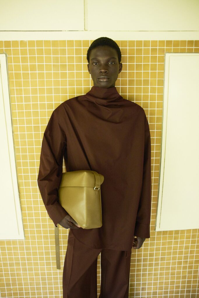 A relaxed brown long-sleeve top with a high-neck and asymmetric design paired with matching pants.